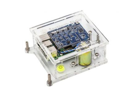 A Raspberry Shake 4D: a green sensor board with a vertical geophone, in a clear acrylic case.